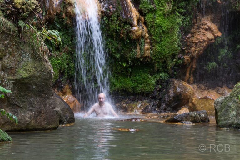 Mann badet unter einem Wasserfall an der Caldera Velha