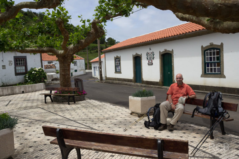 Mann rastet auf einer Bank auf dem Dorfplatz von Fajãzinha
