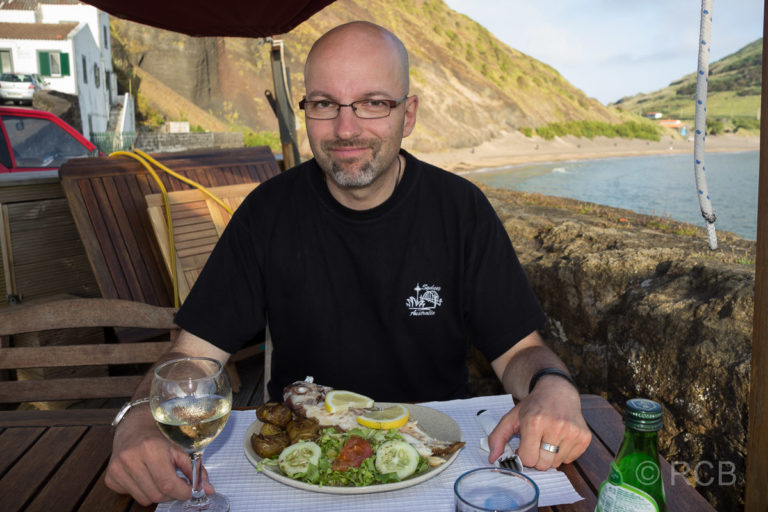 Horta, Mann beim Abendessen am alten Hafenbecken Porto Pim