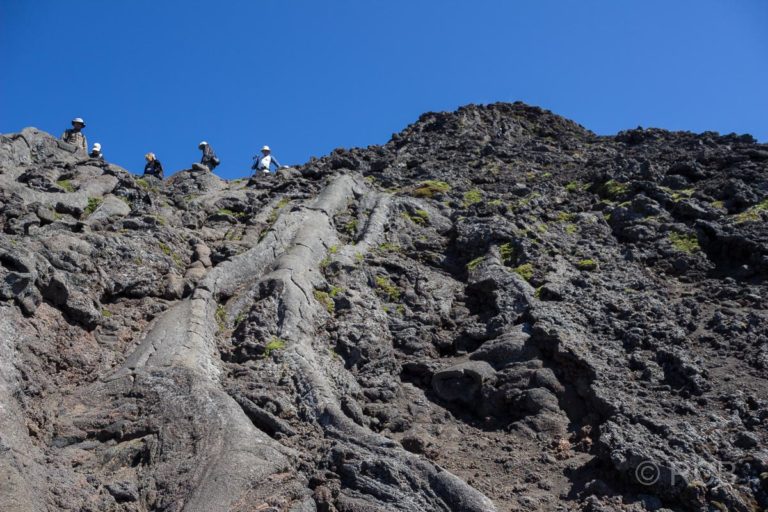 Menschen kommen einen steilen, von erstarrter Lava überzogenen Hang hinab vom Pico Pequenho