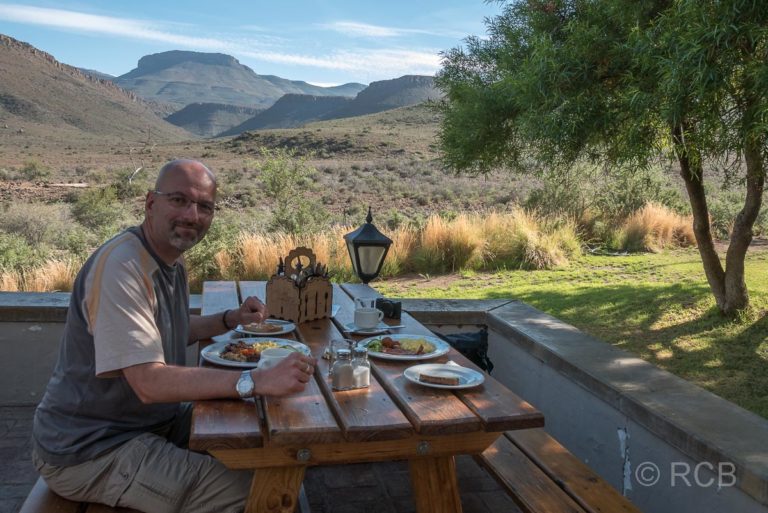 Mann beim Frühstück auf einer Terrasse im Karoo NP