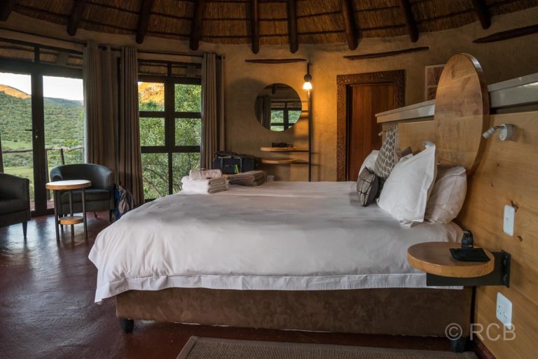 Bett in einer Lodge mit Blick über die grüne Landschaft, Addo Elephant National Park
