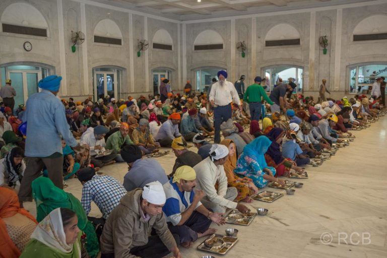 Menschen essen in langen Reihen bei der Speisung im Sikh-Tempel Bangla Sahib Gurudwara, Delhi