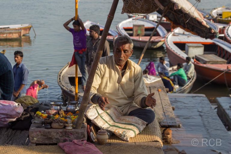 Varanasi, Mann unter einem Sonnenschirm an den Ghats