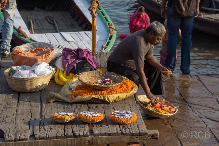 Varanasi, Mann präpariert Blumenschiffchen zum Verkauf an den Ghats