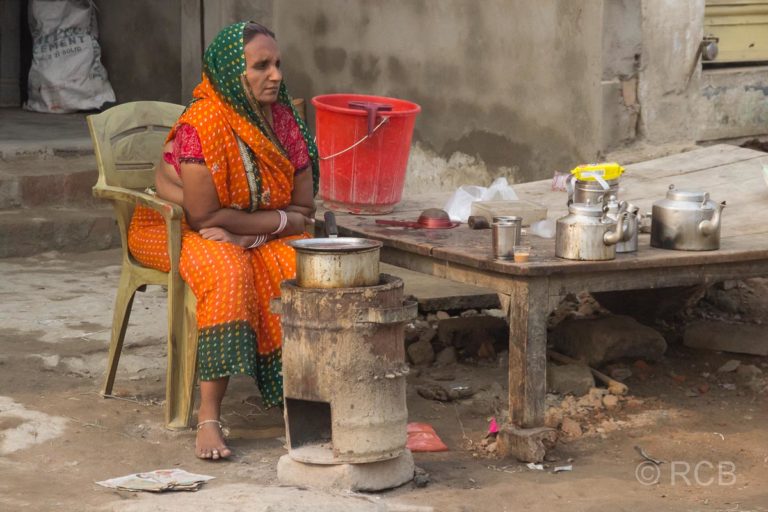 Varanasi, Frau sitzt am Straßenrand und kocht auf einem Kanonenofen