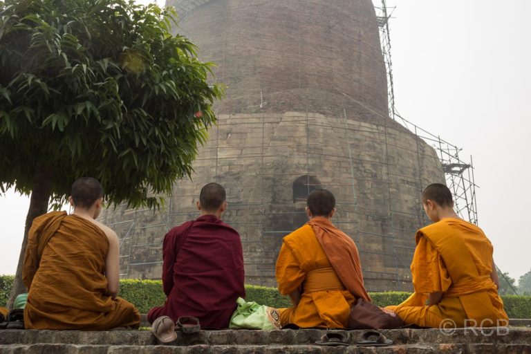 Sarnath, buddhistische Mönche sitzen vor einer großen Stupa