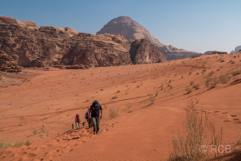 Wanderer steigen auf die höchste Sanddüne des Wadi Rum