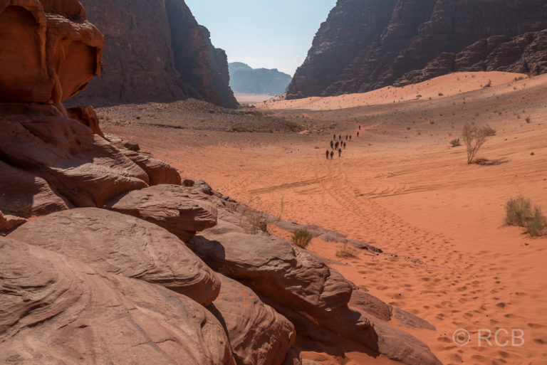Wanderer entfernen sich von der höchsten Sanddüne des Wadi Rum