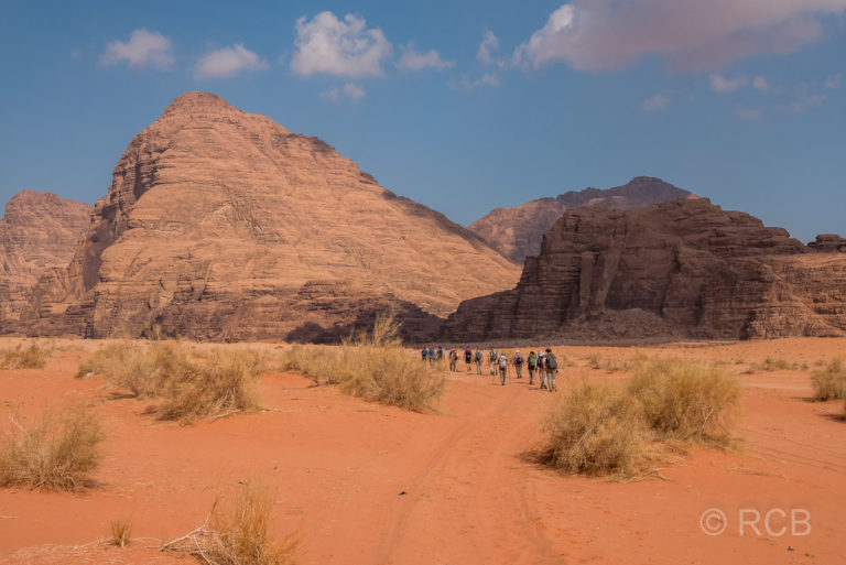 Wanderer laufen im Wadi Rum auf Felsen zu