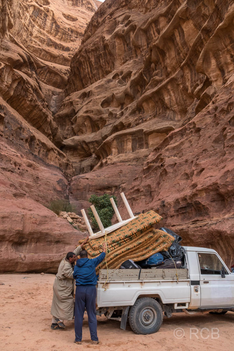 Beduinen laden Sitzkissen und einen Tisch auf einen Pickup im Wadi Rum