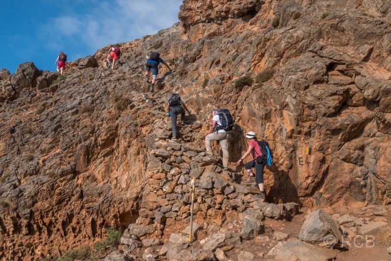 Wanderer ersteigen eine Treppe bei einem ausgesetzten Aufstieg auf dem Küstenpfad des E4