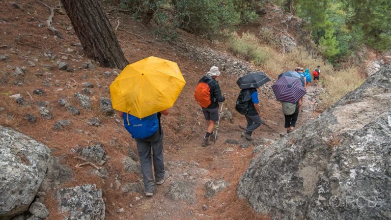 Wanderer mit Regenschirmen in der Irini-Schlucht