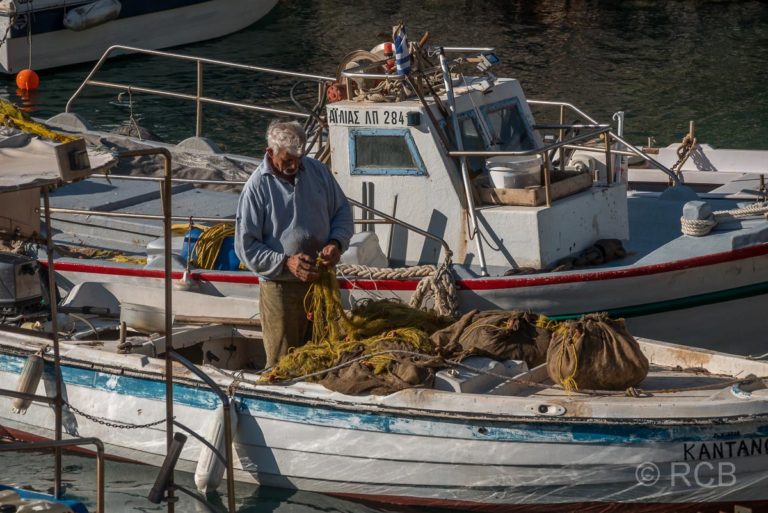 Fischer in seinem Boot beim Flicken der Netze im Hafen von Sougia