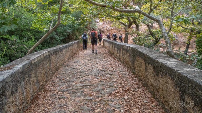 Wanderer passieren eine Brücke mit Herbstlaub in Azogyres