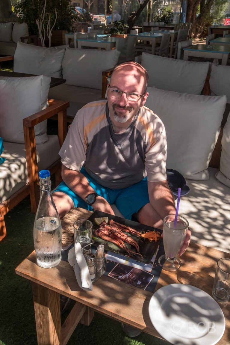 Mann isst Oktopus zum Abschluss seines Urlaubs am Strand von Paleochora