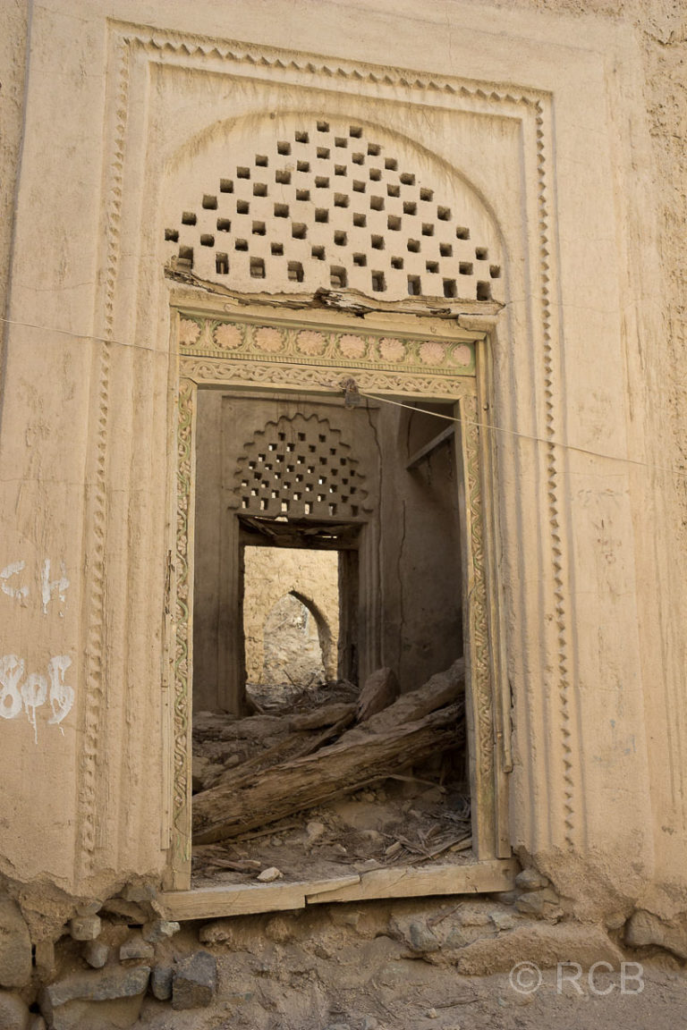 geschnitzte Holztür an einer Hausruine in Al Minzafah