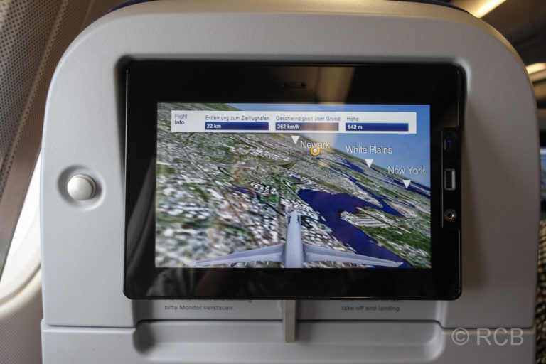 Monitor im Flugzeugsitz mit dem Bild eines Flugzeugs im Anflug auf Newark