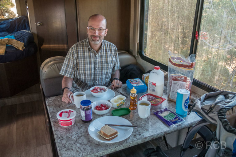 Mann frühstückt im Wohnmobil
