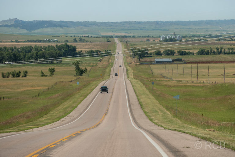 schnurgerade Straße in weiter, welliger Landschaft in Nebraska