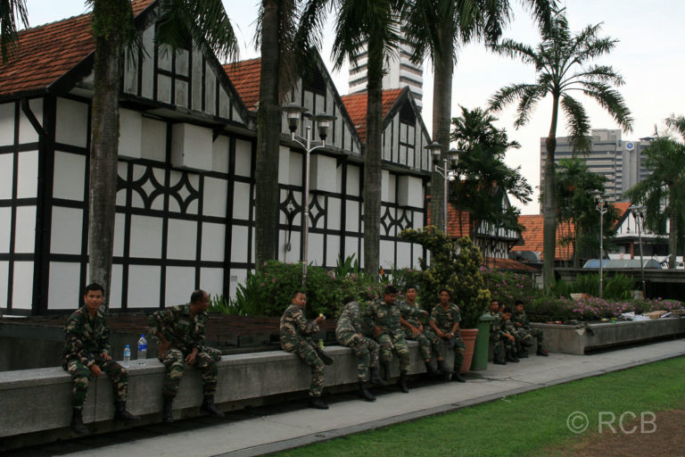malaysische Soldaten sitzen vor Fachwerkhäusern im englischen Stil auf dem Merdeka Square