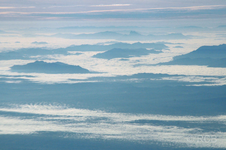 Berge ragen aus den Wolken beim Flug über Sarawak