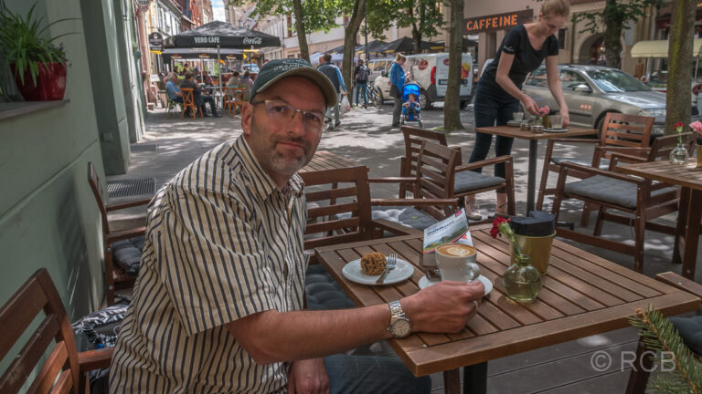 Mann isst Kaffee und Kuchen in der Altstadt von Vilnius
