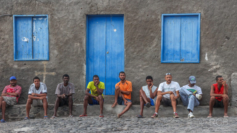 Männer sitzen vor einem Haus in Cruzinha da Garça