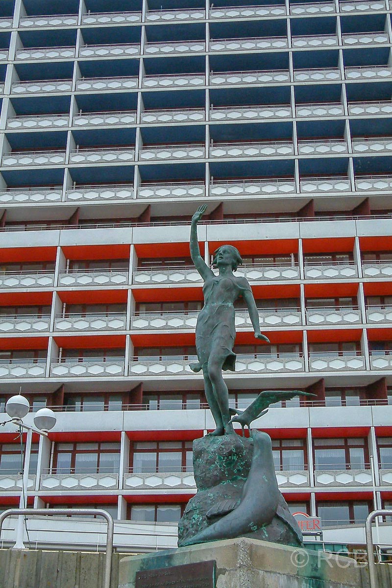 Bronzefigur "S.O.S - Save our Seas" vor dem Hochhaus am Strand von Westerland mit dem Charme der 60er