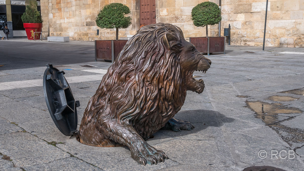 Denkmal eines Löwen, der aus einem Gullydeckel steigt.