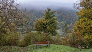 Bank mit Blick auf ein Dorf im Tal